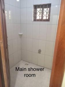 un bagno piastrellato bianco con un bagno principale con doccia di Dawhenya Bungalow 2 a Tema