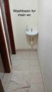 bagno con lavandino e pavimento piastrellato di Dawhenya Bungalow 2 a Tema Altre 3 foto