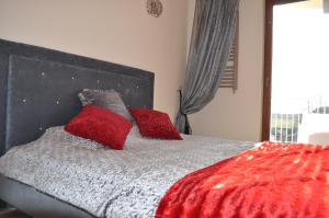 a bedroom with a bed with red pillows on it at Apartament Cristal in Karwia