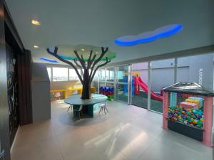 een kamer met een boom, een tafel en een speeltuin bij RN Studio Premium 103 Vista Mar in Maceió