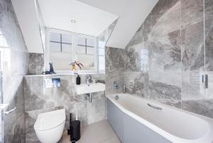 a bathroom with a tub and a toilet and a sink at 4 Bed Townhouse in Uxbridge Ideal For Families or Contractors By AV Stays Short Lets in Hillingdon +55 photos