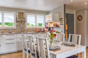 een keuken met een witte tafel met stoelen en een eetkamer bij Les Bicoques à la mer - "Un air de Bicoque" in Dives-sur-Mer