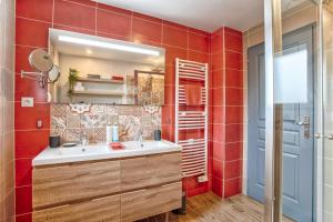een badkamer met een wastafel, een spiegel en rode tegels bij Les Bicoques à la mer - "Un air de Bicoque" in Dives-sur-Mer