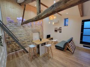 a room with a table and chairs and a stone wall at Le gîte du Verger - Appartement à Arc et Senans in Arc-et-Senans