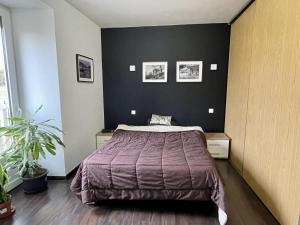 a bedroom with a bed and a black wall at La GALERIE in Onet le Château
