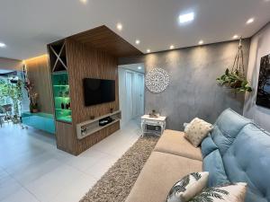 a living room with a blue couch and a tv at Conforto e Estilo - Enxoval Completo - Bertioga in Bertioga