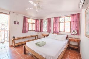 a bedroom with a large white bed and windows at The Ceiba House in Rivas