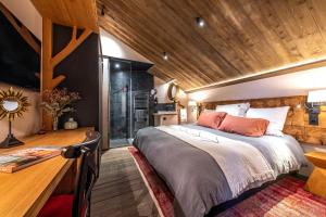 sypialnia z dużym łóżkiem i drewnianym sufitem w obiekcie La Grange aux Hirondelles -5 étoiles- Saint-Malo w Saint-Malo