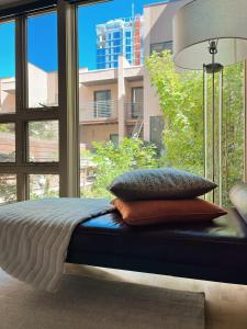 a bed with pillows on it in front of a window at 1 bed apartment with parking - Denver Museum District Walk to Convention Center, Capital, museums and shops in Denver