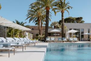 a hotel pool with lounge chairs and palm trees at Sezz Saint-Tropez in Saint-Tropez