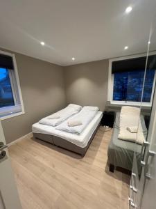 a bedroom with two beds and two windows at Modern apartment with free parking in Bergen