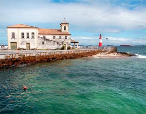 un faro e un edificio con un faro rosso e bianco di Linda Kitnet Mobiliada 03 a Salvador