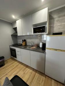 a kitchen with white cabinets and a white refrigerator at Duplex Moderno Perto da Praia in Armação de Pêra