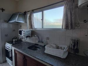 Una pequeña cocina con fregadero y ventana. en Casa Amplia Avenida Solari, en La Paloma 32 fotos más