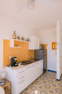 a kitchen with white cabinets and an orange wall at Appartamento Mare Blu in Sciacca +29 photos