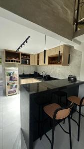 a kitchen with a black counter and two stools at Loft Mauricio in Triunfo +7 photos
