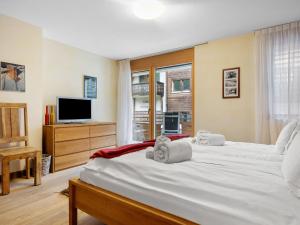 a bedroom with two white beds and a television at Apartment Rütschi-9 by Interhome in Zermatt