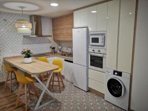 a kitchen with a table with chairs and a refrigerator at A casa da mãe in Olivenza