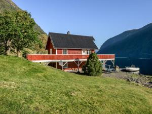 a red house on a hill next to a lake at Holiday Home Tor by Interhome in Arnefjord