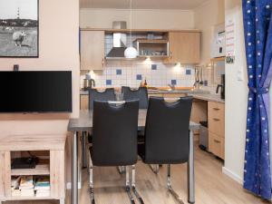 a kitchen with a table with chairs and a tv at Holiday Home Kiel by Interhome in Norddeich +30 photos