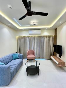 a living room with a blue couch and a tv at Peacock Palace 2BHK Modern AC Flat in Baner Pune in Pune