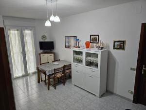 a kitchen with a table and a white cabinet at Sardinia Holiday e Services srls Costa in Alghero +5 photos