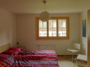 a bedroom with a bed and a window and a chair at Apartment Lucie by Interhome in Adelboden +3 photos