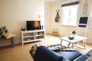 a living room with a couch and a tv at Fonte do Cabo Apartment in Ericeira