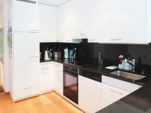 a kitchen with white cabinets and black counter tops at Apartment Sonnenbergweg 5 by Interhome in Engelberg