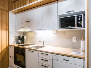 eine Küche mit weißen Schränken und einer Mikrowelle in der Unterkunft Holiday Home Lomakatti 10b by Interhome in Vuokatti