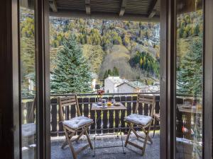 a table and chairs on a balcony with a view at Apartment Isola di Madesimo Apartments-1 by Interhome in Isola