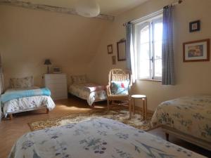 a bedroom with two beds and a chair and a window at La Ferme du Chateau in Fauguernon