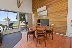 Un comedor con mesa y sillas y un televisor. en Steamer - Waterfront Retreat, en Goon Nure