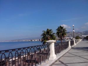 a white fence next to the water with palm trees at Mariam Royal Apartment & Rooms in Reggio Calabria +16 photos