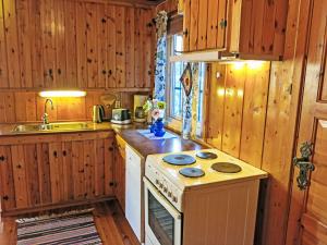 a kitchen with a stove and a sink and wooden cabinets at Holiday Home Midtholmen by Interhome in Konsmo