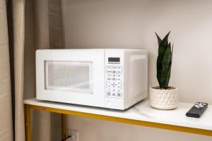 eine Mikrowelle auf einem Regal mit einer Pflanze in der Unterkunft Bright & Stylish Modern Townhome in Oakville! in Oakville + 40 Fotos