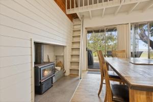 comedor con estufa de leña y mesa en Westwind - Waterfront Retreat, en Goon Nure