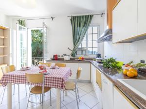 una cocina con mesa y sillas y una cocina con encimeras blancas en Apartment Il Risveglio-6 by Interhome, en Imperia