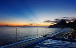 a swimming pool with a view of the ocean at sunset at Sol Ipanema Hotel in Rio de Janeiro