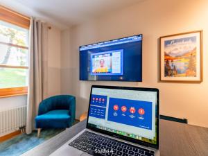 a laptop sitting on a table in a room with a tv at Apartment Steil Alva Studios Smit by Interhome in Lenzerheide