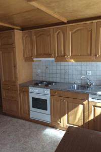 - une cuisine avec des placards en bois, une cuisinière et un évier dans l'établissement Apartment Miranda by Interhome, à Saas-Almagell
