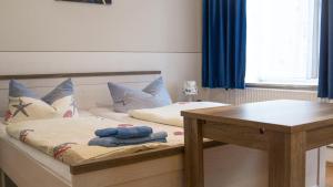 a bedroom with two beds and a wooden table at Hotel Restaurant Nordpol in Heiligenhafen +8 photos