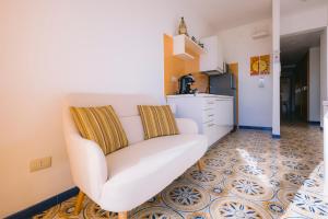 a living room with a white chair and a kitchen at Appartamento Mare Blu in Sciacca