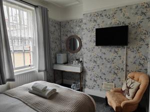 a bedroom with a bed and a mirror and a chair at Lichfield House in Weymouth