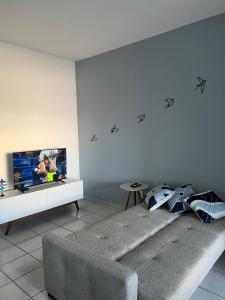 a living room with a couch and a flat screen tv at Novidade na Enseada Azul! Apto com churrasqueira, área gourmet e Ar condicionado a 150m da praia in Guarapari