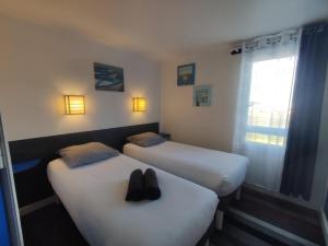 two beds with shoes on them in a room at Kyriad Direct Saintes in Saintes