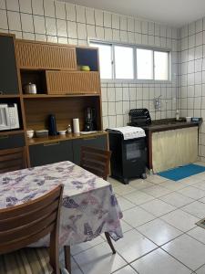 a kitchen with a table and a kitchen with a stove at Novidade na Enseada Azul! Apto com churrasqueira, área gourmet e Ar condicionado a 150m da praia in Guarapari