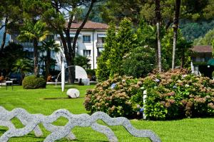 a sculpture in a park with a building and flowers at Villa Delta Suites House in Ascona