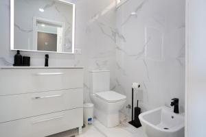 a white bathroom with a toilet and a sink at Apartamento Frente Oceano in Puerto de la Cruz +36 photos