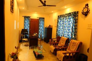 uma sala de estar com cadeiras e uma ventoinha de tecto em Heather Home Stay em Cochin